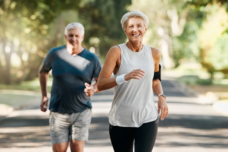 older woman smiling while running with her husband